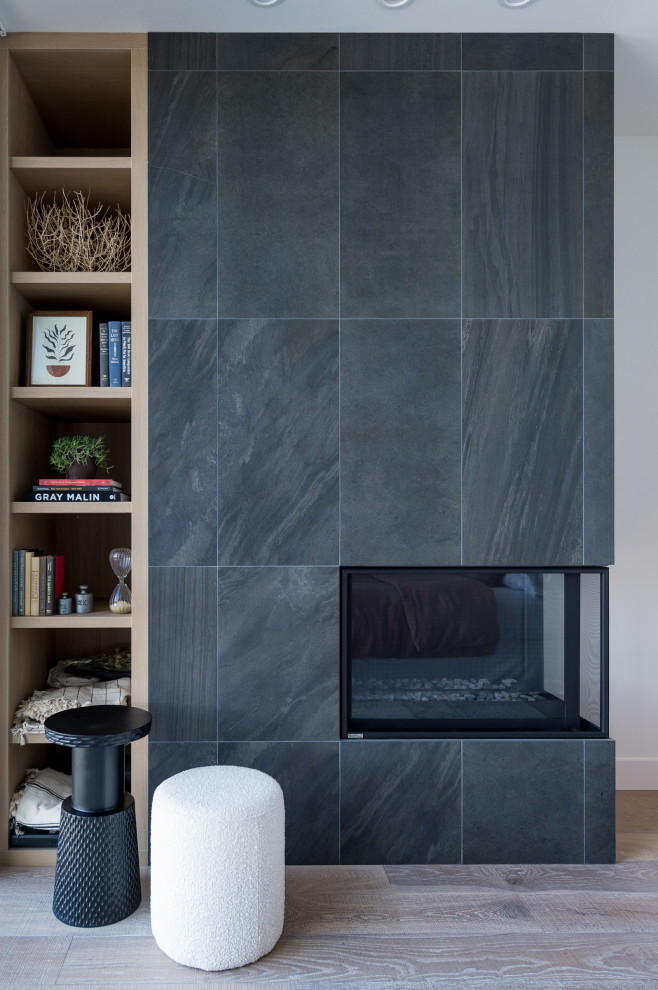 شومینه مدرن با پوشش سنگ تیره و طراحی یکپارچه در کنار قفسه چوبی، تلفیقی از گرما، زیبایی و سادگی در دکوراسیون داخلی
