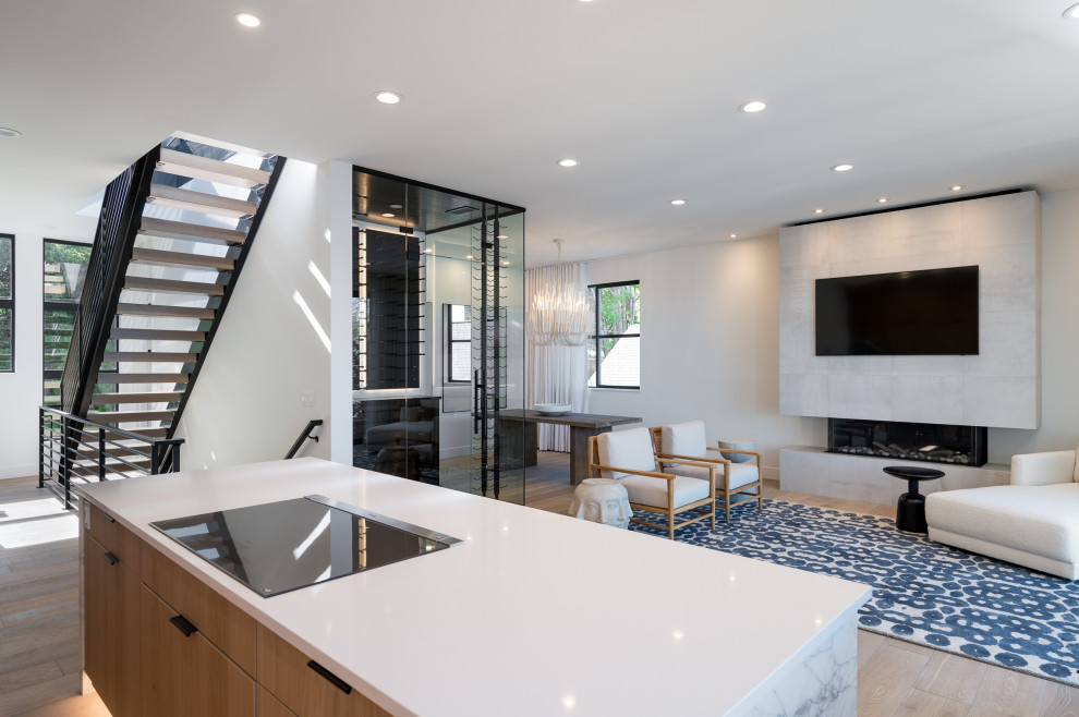 طراحی داخلی مینیمال با پلکان معلق مدرن، جزیره آشپزخانه سفید، شومینه دیواری و فضای نشیمن با نور طبیعی فراوان
