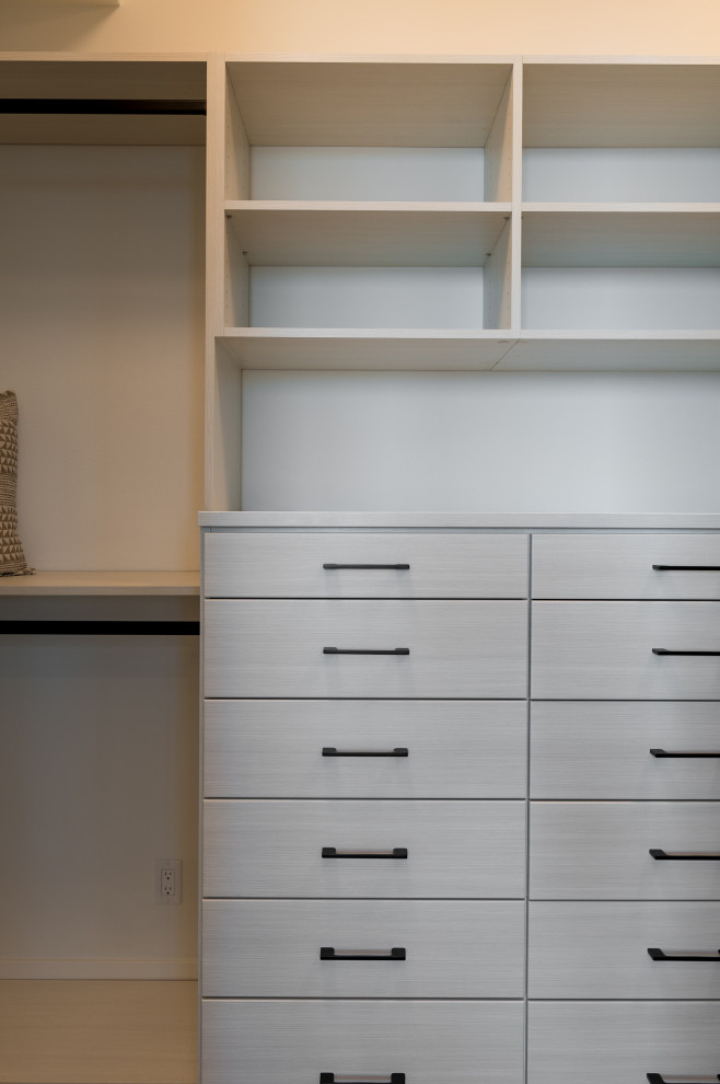 طراحی کلوزت مدرن با کشوهای سفید مات، دستگیره‌ مشکی مینیمال و قفسه‌های باز برای نظم‌دهی و چیدمان کاربردی لباس
