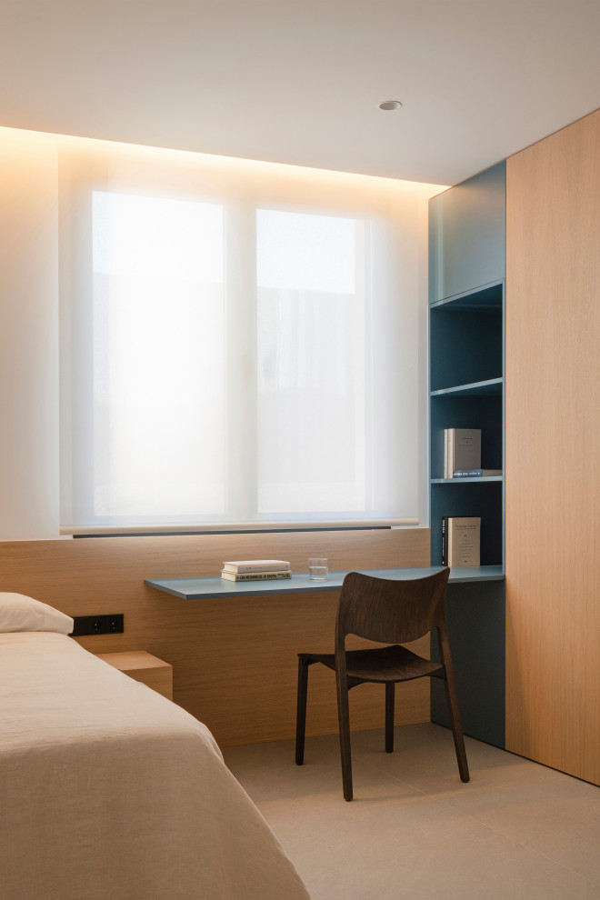 اتاق خواب مدرن با طراحی مینیمال، تخت ساده با روکش کرم، میز تحریر معلق به رنگ آبی مات، قفسه و کمد چوبی یکپارچه، نور پشت پرده حریر