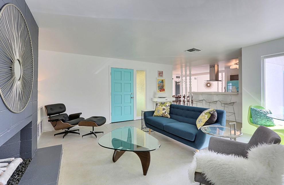 دکوراسیون داخلی نشیمن با سبک مدرن دهه ۵۰، مبلمان مینیمال، درب آبی، شومینه بتنی و نور طبیعی در طراحی پلان باز خانه
