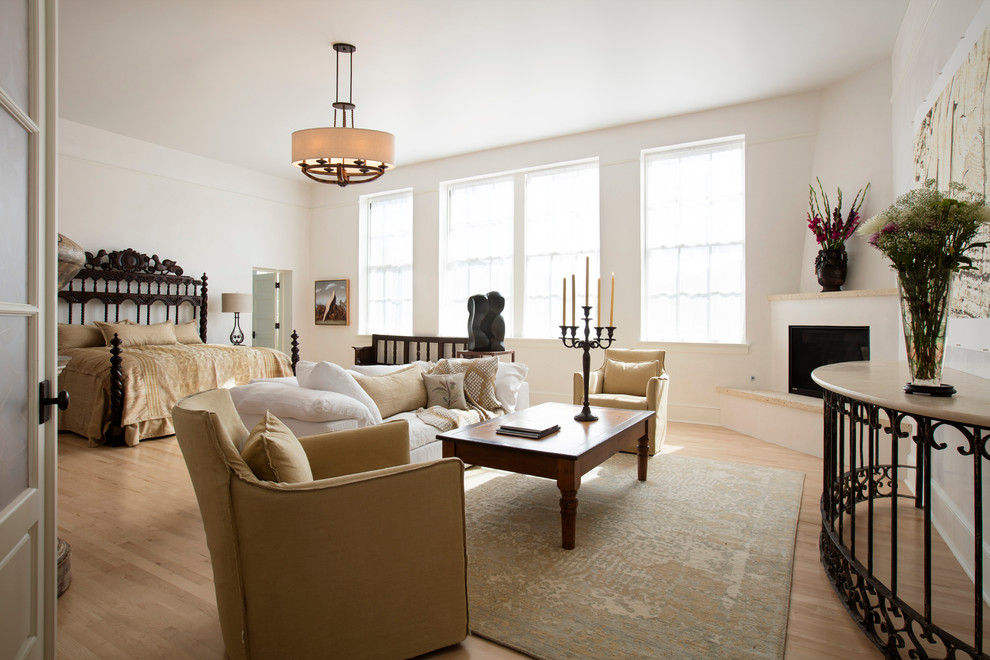 ایده طراحی اتاق خواب بزرگ مستر سنتی با ابعاد متوسط؛ دارای کف‌پوش چوبی با رنگ متوسط، دیوارهای سفید، شومینه گوشه‌ای با پوشش گچی