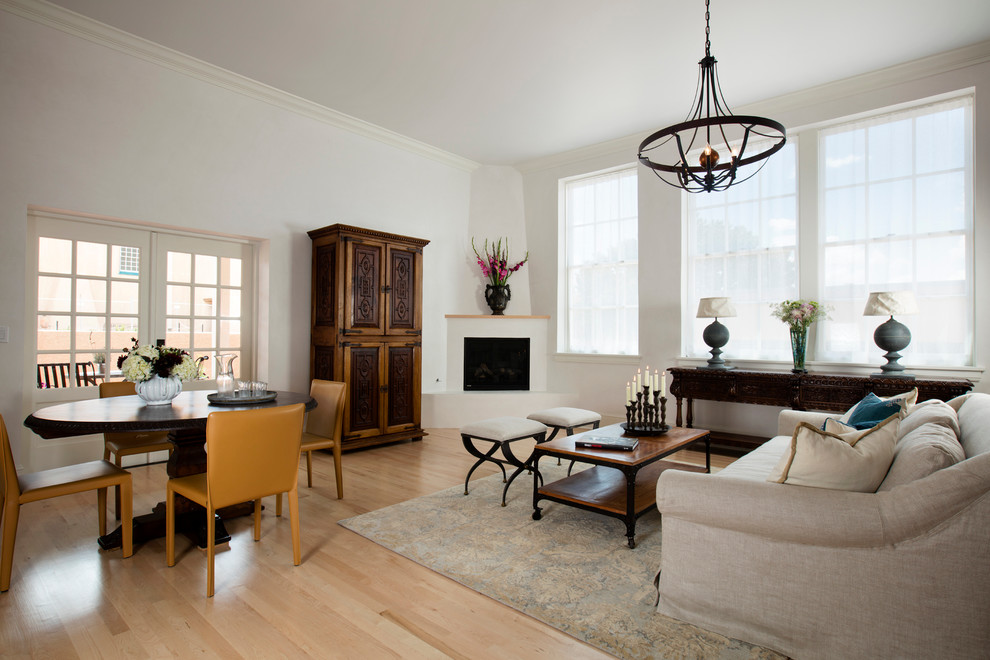 طراحی نشیمن سنتی و دنج با ابعاد متوسط؛ دارای کف‌پوش چوبی روشن، دیوارهای سفید، شومینه گوشه‌ای با پوشش گچی و تلویزیون مخفی‌شده