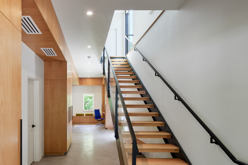 راه‌پله داخلی با طراحی مینیمال و استفاده از چوب طبیعی در خانه مدرن پربازده انرژی - Internal staircase with minimalist design and natural wood in a modern energy-efficient home.