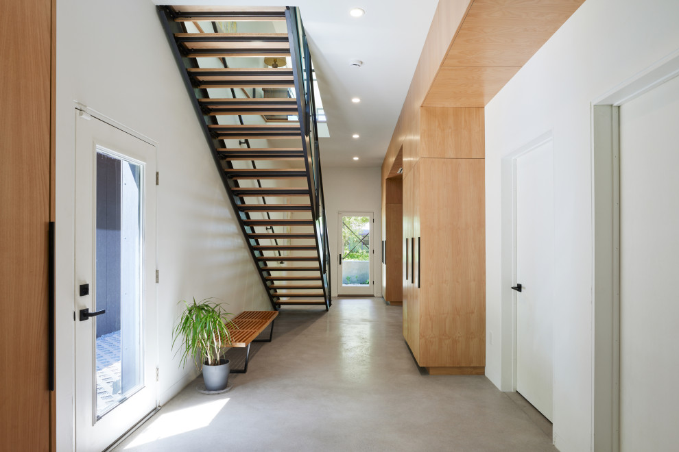 راهروی ورودی خانه مدرن با راه‌پله فلزی و چوبی، دیوارهای سفید، کمدهای چوبی سفارشی 
Modern home entry hallway with wood and metal staircase white walls custom wood cabinetry