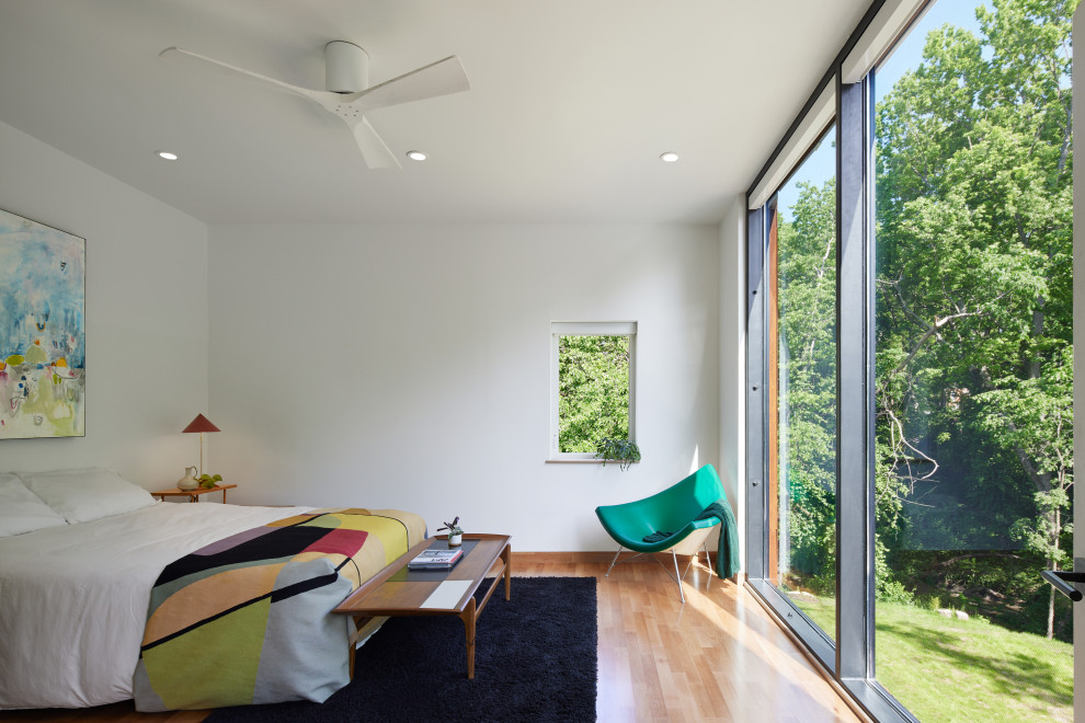 اتاق خواب مدرن با پنجره تمام‌قد ، دکوراسیون مینیمال و کف‌پوش چوبی روشن - Modern bedroom with floor-to-ceiling windows overlooking greenery minimalist decor and light wood flooring