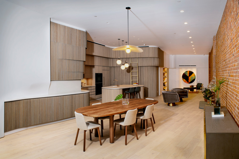فضای یکپارچه و مدرن شامل آشپزخانه با طراحی منحنی، میز ناهارخوری چوبی، دیوار آجری نمایان Open-concept modern interior with curved wood kitchen wooden dining table exposed brick wall