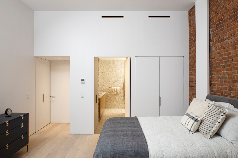 اتاق خواب مدرن مستر با دیوار آجری، کمدهای سفید و سرویس بهداشتی با طراحی سنگریزه‌ای
Modern master bedroom with a brick wall white closets and a pebble-style bathroom design.