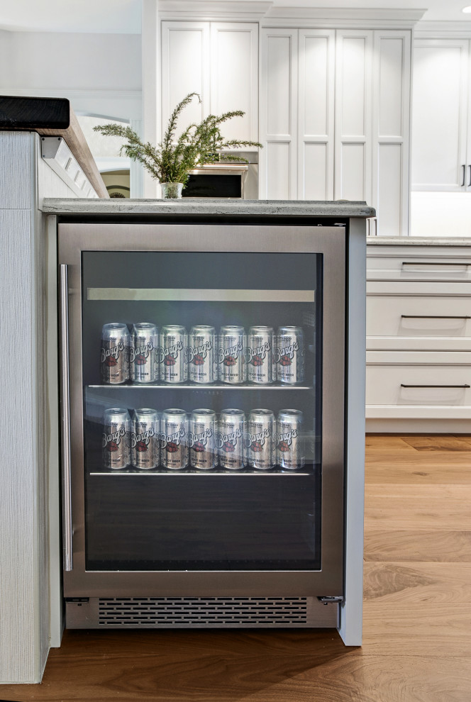 یخچال نوشیدنی توکار با درب شیشه‌ای و بدنه استیل، یکپارچه با جزیره آشپزخانه مدرن و کابینت‌های سفید کلاسیک