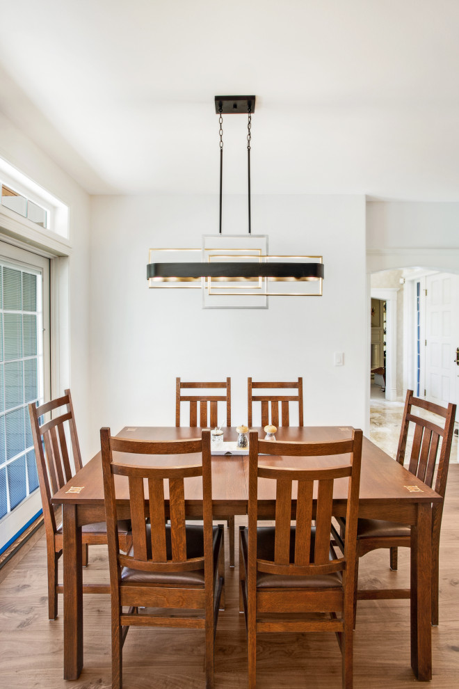 سالن غذاخوری با میز و صندلی چوبی هشت‌نفره، کف‌پوش چوبی و لوستر مدرن معلق با طراحی هندسی در فضایی روشن و ساده