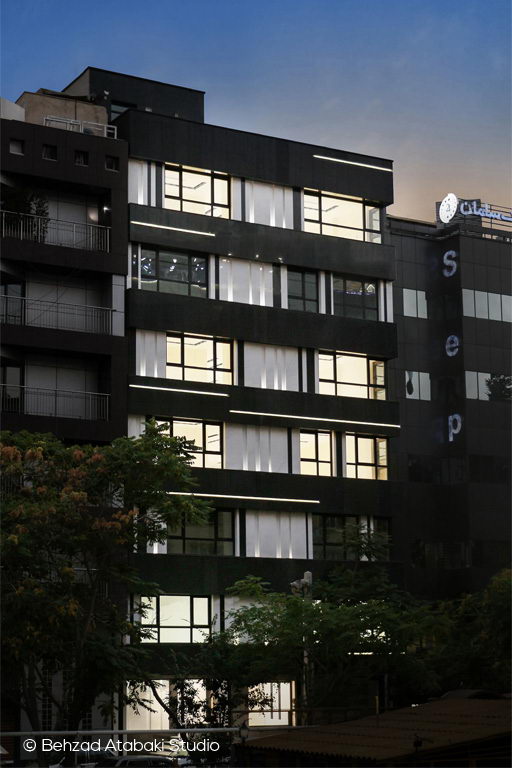 نمای شب ساختمان اداری مدرن با نمای مشکی، خطوط نور مخفی افقی و پنجره‌های سرتاسری در طراحی معاصر شهری